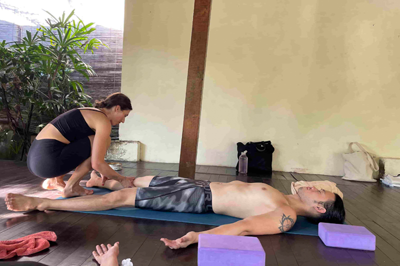 Yoga student practicing a long-held Yin Yoga pose with a bolster to stimulate fascia health and nervous system recovery.